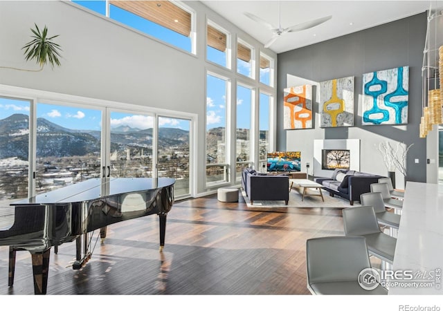 living room with wood-type flooring, a mountain view, a towering ceiling, and a wealth of natural light