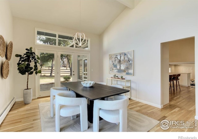 dining room with baseboard heating, high vaulted ceiling, and light hardwood / wood-style flooring