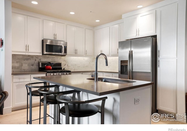 kitchen featuring white cabinetry, a breakfast bar area, an island with sink, and tasteful backsplash