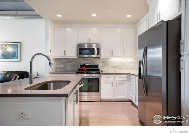 kitchen with stainless steel appliances, sink, white cabinets, and backsplash