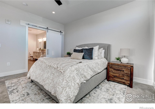 bedroom featuring ceiling fan, connected bathroom, and a barn door