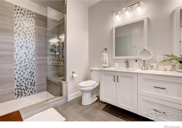 bathroom with tile patterned floors, vanity, toilet, and a tile shower