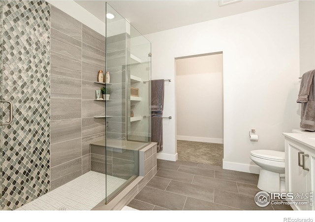 bathroom featuring toilet, vanity, and a shower with shower door