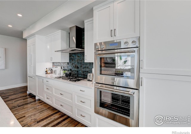 kitchen featuring white cabinetry, tasteful backsplash, wall chimney exhaust hood, and appliances with stainless steel finishes