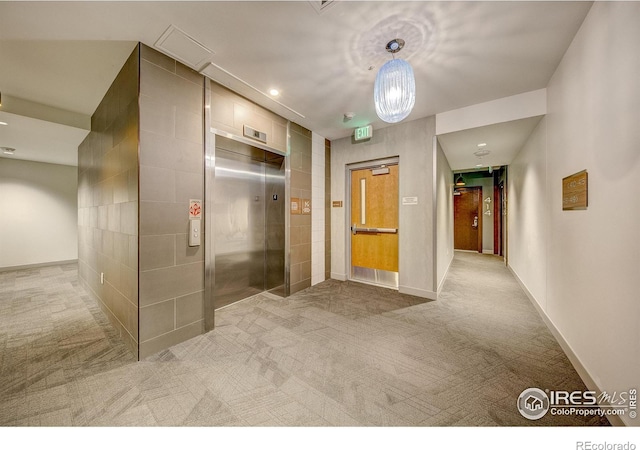 hall with elevator and light colored carpet