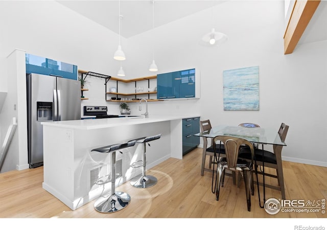 kitchen featuring hanging light fixtures, appliances with stainless steel finishes, blue cabinetry, and a kitchen bar