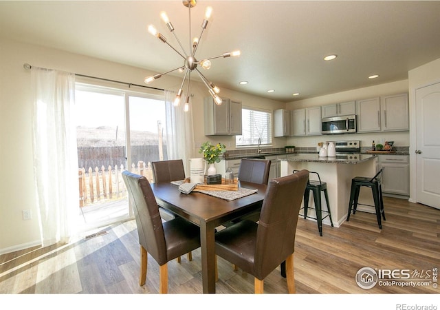 dining space featuring sink, an inviting chandelier, and light hardwood / wood-style flooring