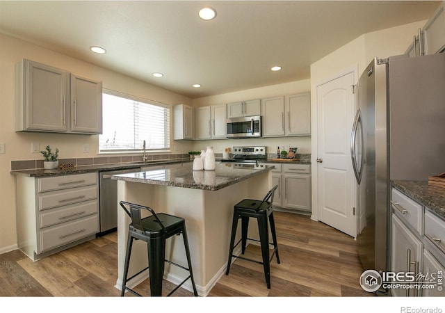 kitchen featuring sink, a breakfast bar area, a center island, dark hardwood / wood-style floors, and stainless steel appliances