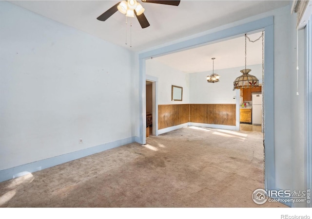 carpeted spare room featuring ceiling fan and wooden walls