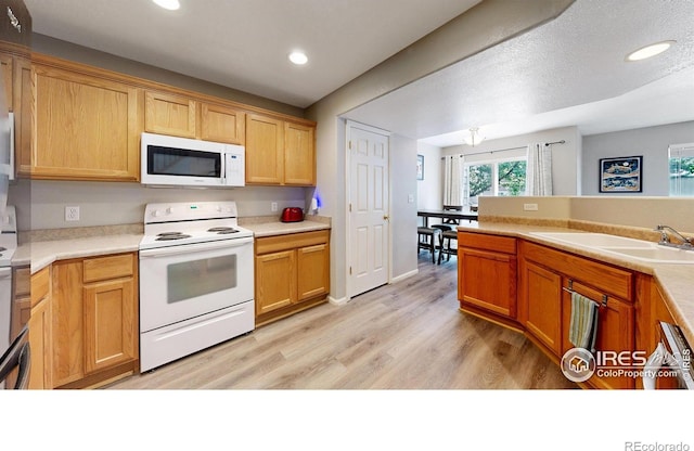 kitchen featuring white appliances, sink, and light hardwood / wood-style flooring