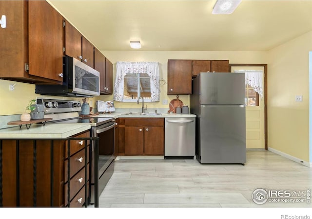 kitchen featuring appliances with stainless steel finishes, sink, and light hardwood / wood-style floors