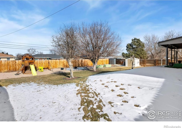 snowy yard featuring a playground