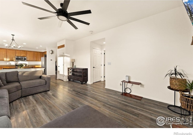 living room with dark wood-type flooring and ceiling fan with notable chandelier