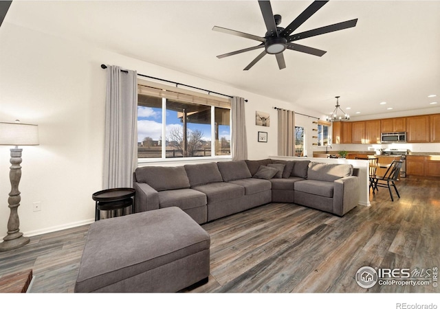 living room featuring dark hardwood / wood-style flooring and ceiling fan with notable chandelier