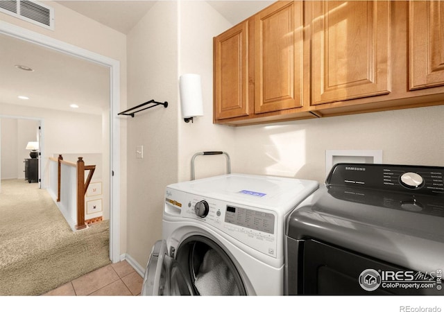 laundry room featuring cabinets, washer and dryer, and light tile patterned floors