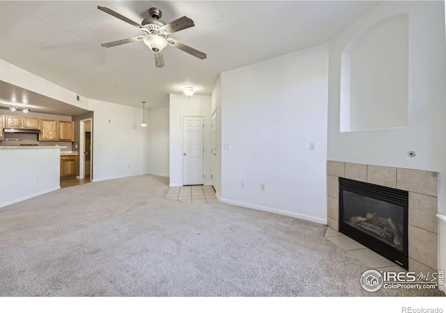 unfurnished living room featuring ceiling fan, a fireplace, and light carpet