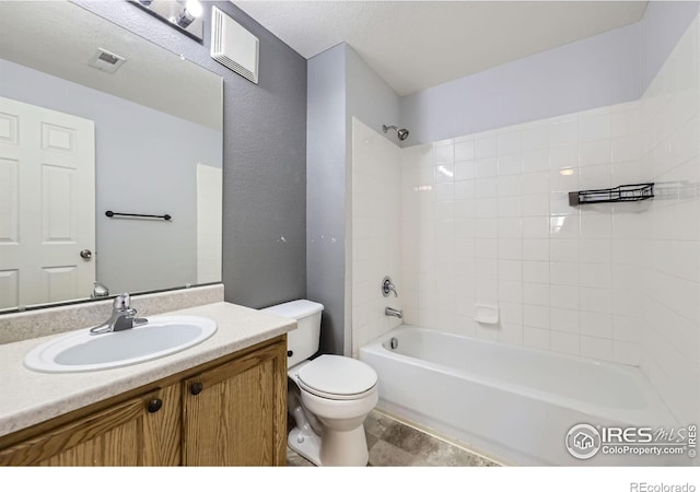 full bathroom with vanity, tiled shower / bath, a textured ceiling, and toilet