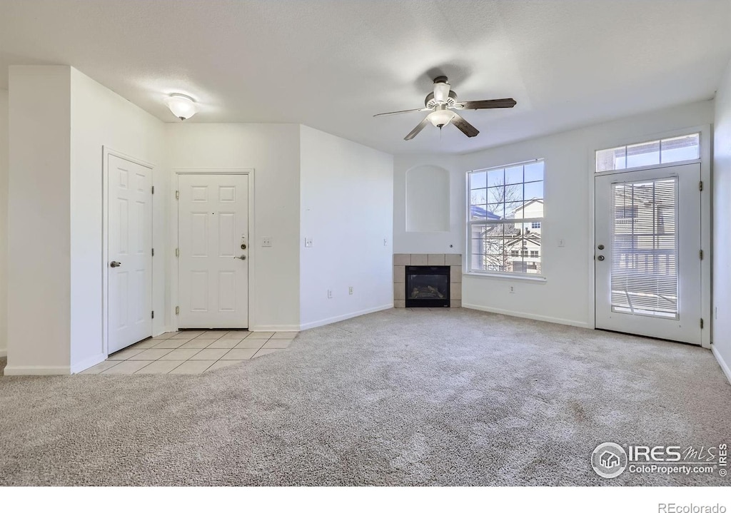 unfurnished living room featuring ceiling fan, a fireplace, and light carpet