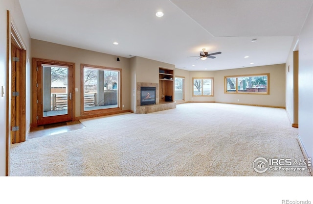 unfurnished living room featuring light colored carpet, a tile fireplace, and ceiling fan