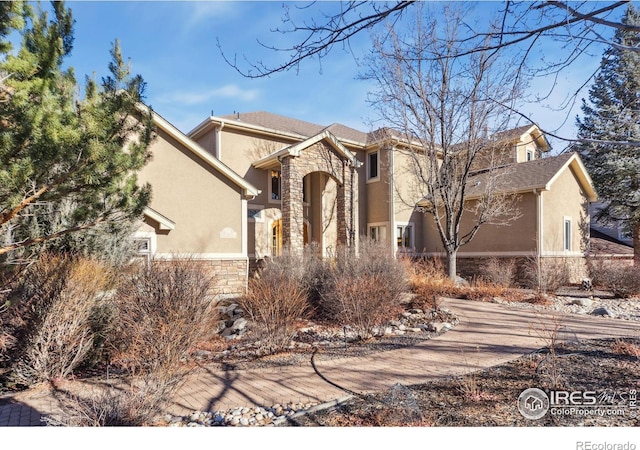 view of front of house featuring stone siding and stucco siding