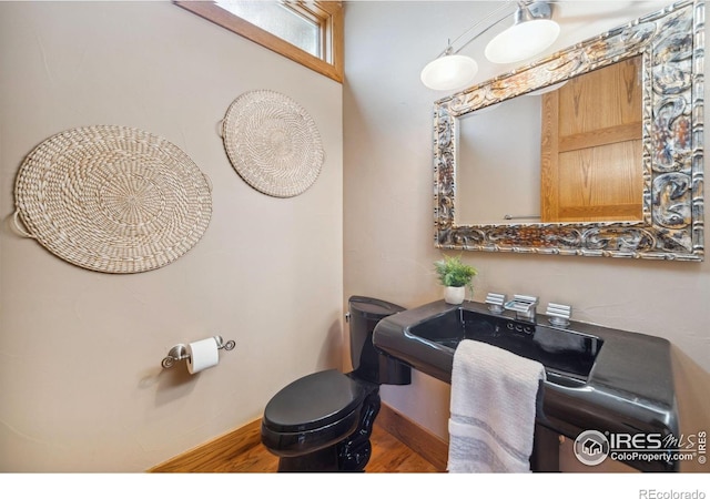 bathroom with wood finished floors, a sink, and toilet