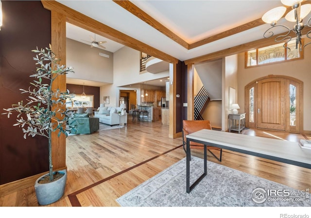 entrance foyer featuring a towering ceiling, stairs, a notable chandelier, and wood finished floors