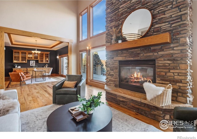 living room featuring a raised ceiling, a fireplace, plenty of natural light, and wood finished floors