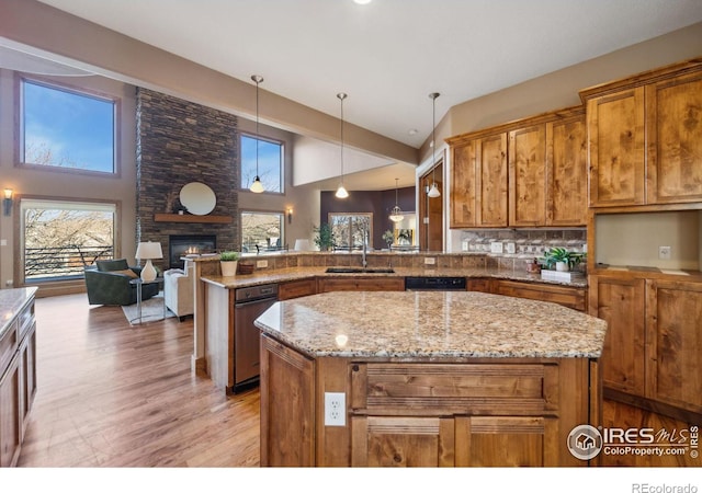 kitchen featuring brown cabinets, a sink, a stone fireplace, and a peninsula