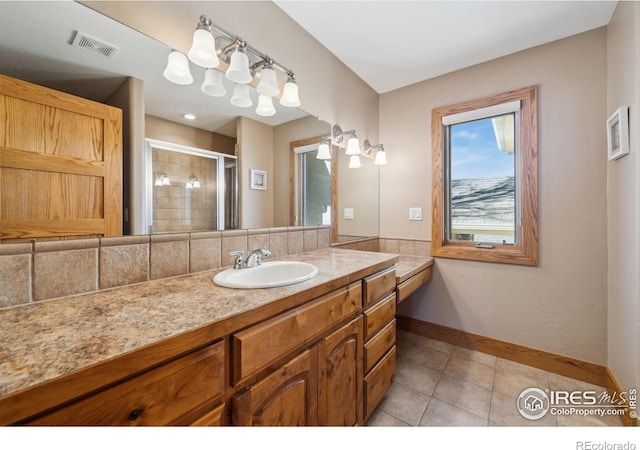 bathroom with tile patterned flooring, vanity, visible vents, baseboards, and a stall shower