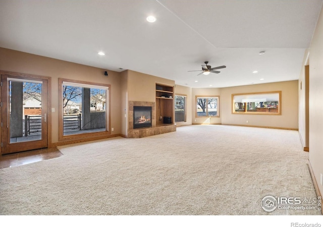 unfurnished living room with carpet floors, plenty of natural light, a fireplace, and recessed lighting