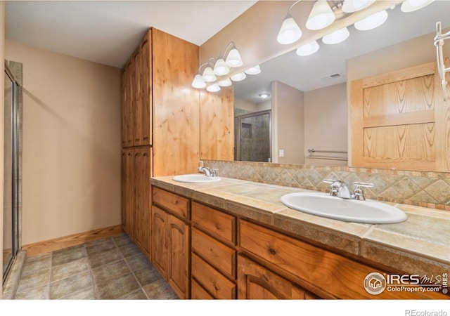 bathroom featuring tasteful backsplash, a stall shower, a sink, and double vanity