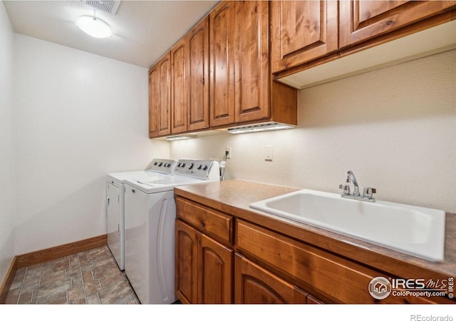 laundry room featuring washing machine and dryer, a sink, visible vents, baseboards, and cabinet space