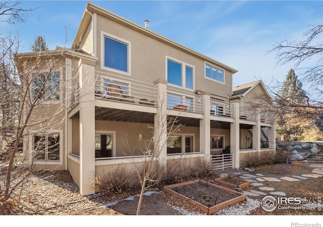 back of house with stairs, a garden, and stucco siding