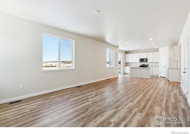 unfurnished living room with light hardwood / wood-style flooring and a wealth of natural light