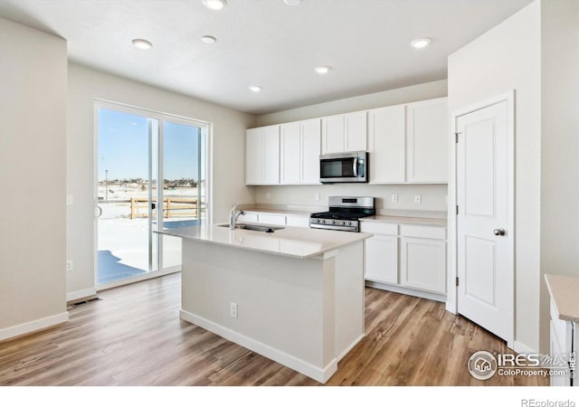 kitchen with white cabinetry, an island with sink, sink, stainless steel appliances, and light wood-type flooring