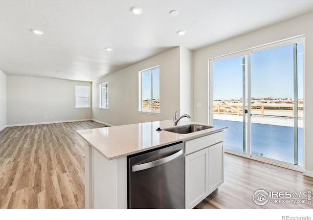 kitchen with sink, white cabinetry, a center island with sink, stainless steel dishwasher, and light hardwood / wood-style floors