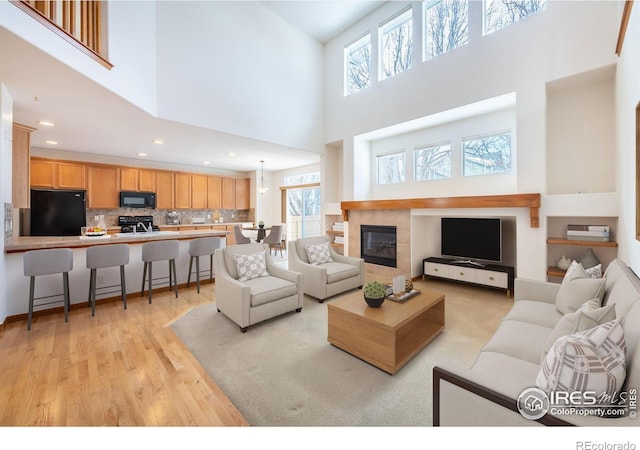 living area featuring recessed lighting, a fireplace, a wealth of natural light, and light wood-style floors