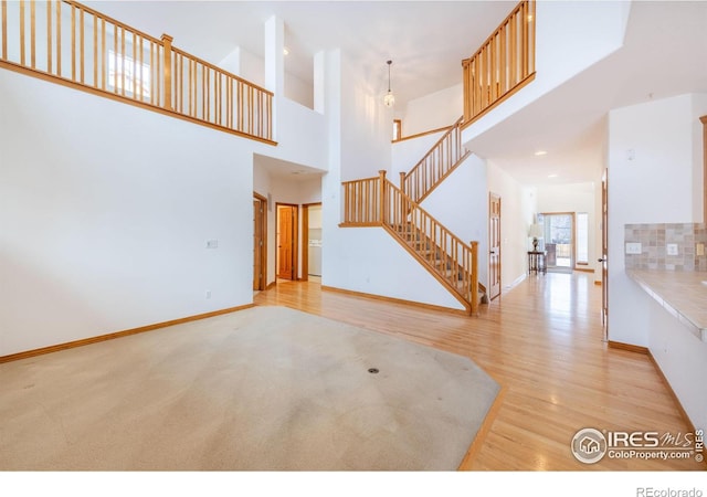 unfurnished living room with a high ceiling and light hardwood / wood-style floors