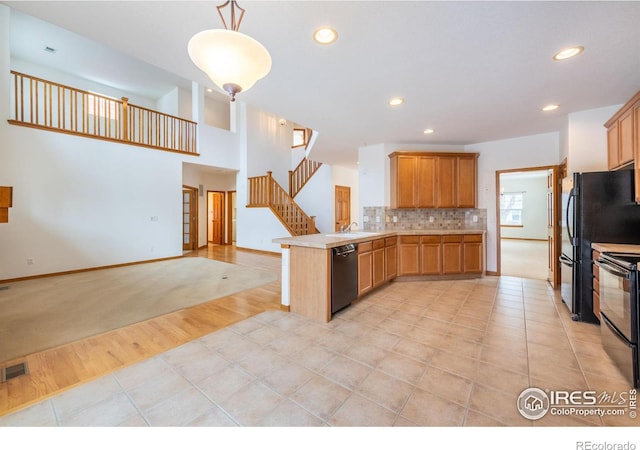 kitchen featuring light tile patterned floors, kitchen peninsula, pendant lighting, decorative backsplash, and black appliances