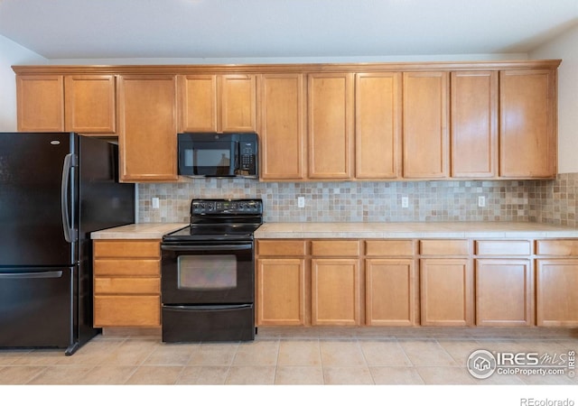 kitchen with backsplash, light tile patterned floors, tile counters, and black appliances