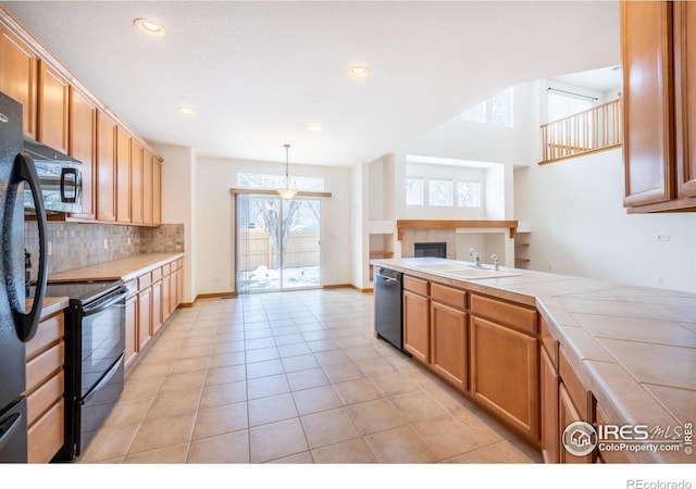 kitchen with sink, tasteful backsplash, black appliances, decorative light fixtures, and tile countertops