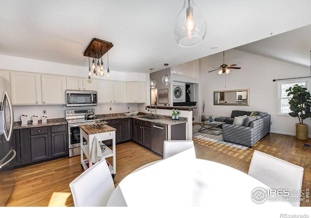 kitchen with pendant lighting, white cabinetry, sink, light stone counters, and stainless steel appliances