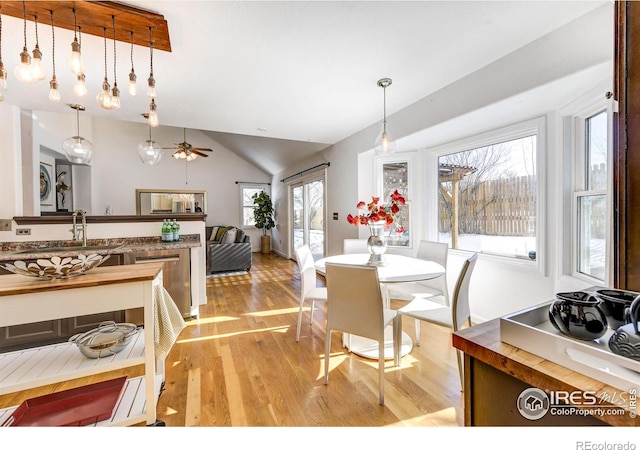 dining space featuring lofted ceiling, sink, and light wood-type flooring