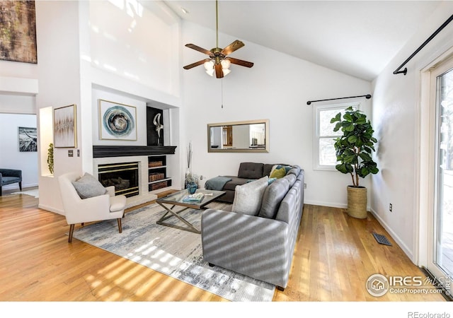 living room featuring a large fireplace, plenty of natural light, high vaulted ceiling, and wood-type flooring