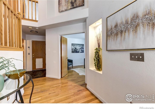 hallway with a towering ceiling and light hardwood / wood-style flooring