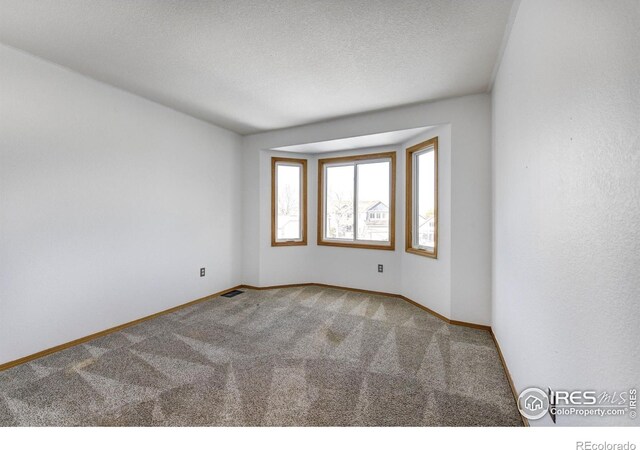 empty room with a textured ceiling and carpet