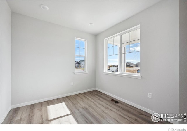 spare room with a healthy amount of sunlight and light hardwood / wood-style flooring