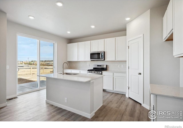 kitchen featuring sink, appliances with stainless steel finishes, white cabinetry, an island with sink, and decorative backsplash