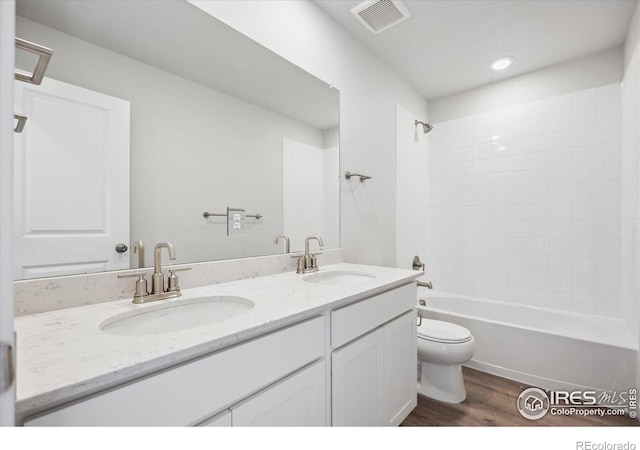 full bathroom with wood-type flooring, toilet, tiled shower / bath combo, and vanity