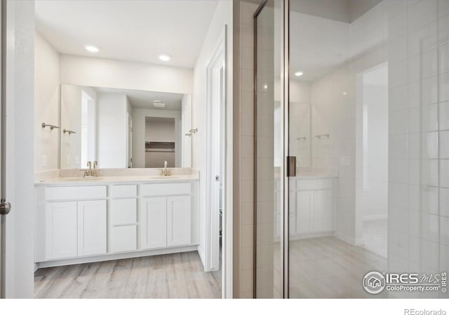 bathroom with vanity, hardwood / wood-style flooring, and a shower with shower door